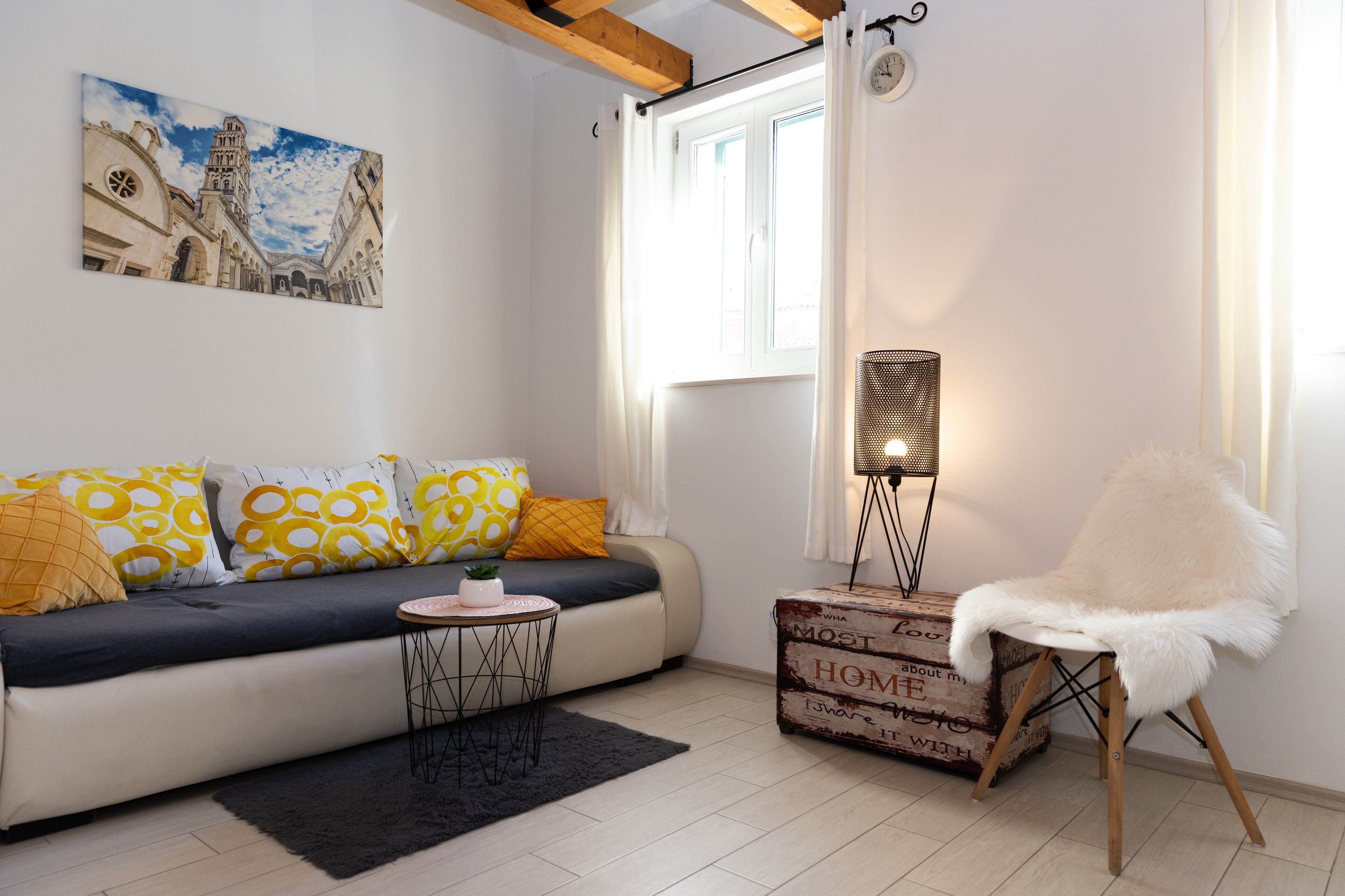 Una sala de estar moderna con un sofá, una mesita redonda, una lámpara de pie y un sillón decorativo.