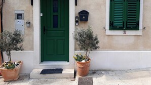 A building with a green door, a sign reading "PAESE", and two potted plants in front. - Rooms and apartments Paese (Split)