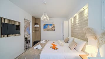 Een moderne hotelkamer met een groot bed, een flatscreen televisie aan de muur, een schilderij van een historisch gebouw en een decoratief wandpaneel.