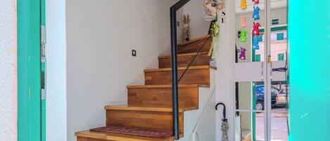 A wooden staircase with a handrail, leading to a door with a glass panel.