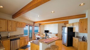 Una cocina amplia con armarios de madera, un refrigerador de acero inoxidable y una isla grande con taburetes.