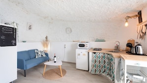 A compact living space with a kitchenette, a blue sofa, a small dining table, and a white refrigerator. - 'Casa Hélène' with Sea Views, Shared Pool and Wi-Fi (Fasnia)