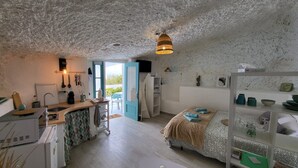 A compact, well-lit room with a kitchenette, a bed, a dining area, and a view through an open door. - 'Casa Hélène' with Sea Views, Shared Pool and Wi-Fi (Fasnia)