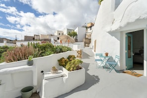 A white-walled building with a patio area, outdoor seating, and potted plants. - 'Casa Hélène' with Sea Views, Shared Pool and Wi-Fi (Fasnia)
