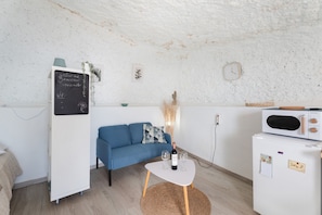 A room with a blue sofa, a white table with a bottle and glasses, a white refrigerator, and a chalkboard with a welcome message. - 'Casa Hélène' with Sea Views, Shared Pool and Wi-Fi (Fasnia)