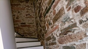 A staircase with white steps and black edges, leading up to a stone wall.