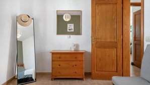 Una habitación con un aparador de madera, un espejo, una puerta y un banco.