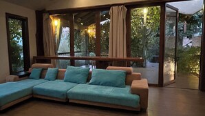 Una sala de estar moderna con un sofá seccional, ventanas amplias y vistas a un jardín.