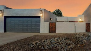 Een modern huis met een garage, een grindpad en een zonsondergang.