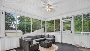 A covered patio with a sectional sofa, a coffee table, and a ceiling fan.