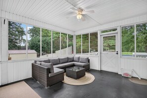A covered patio with a sectional sofa, a coffee table, and a ceiling fan.