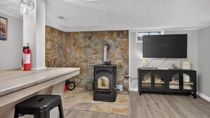 A room with a stone fireplace, a black entertainment unit, and a mounted television.