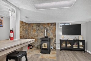 A room with a stone fireplace, a black entertainment unit, and a mounted television.