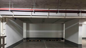 An empty parking garage with concrete walls, a ceiling with exposed pipes, and directional arrows on the floor. - Modern Ñuñoa Apt - Projector & Free Parking (Ñuñoa)