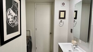 Un bagno con un quadro appeso, un water, un lavandino e uno specchio.
