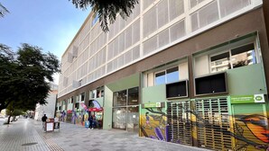 Un edificio con una vetrina verde, un cartello Coca-Cola e un murale sulla parete.