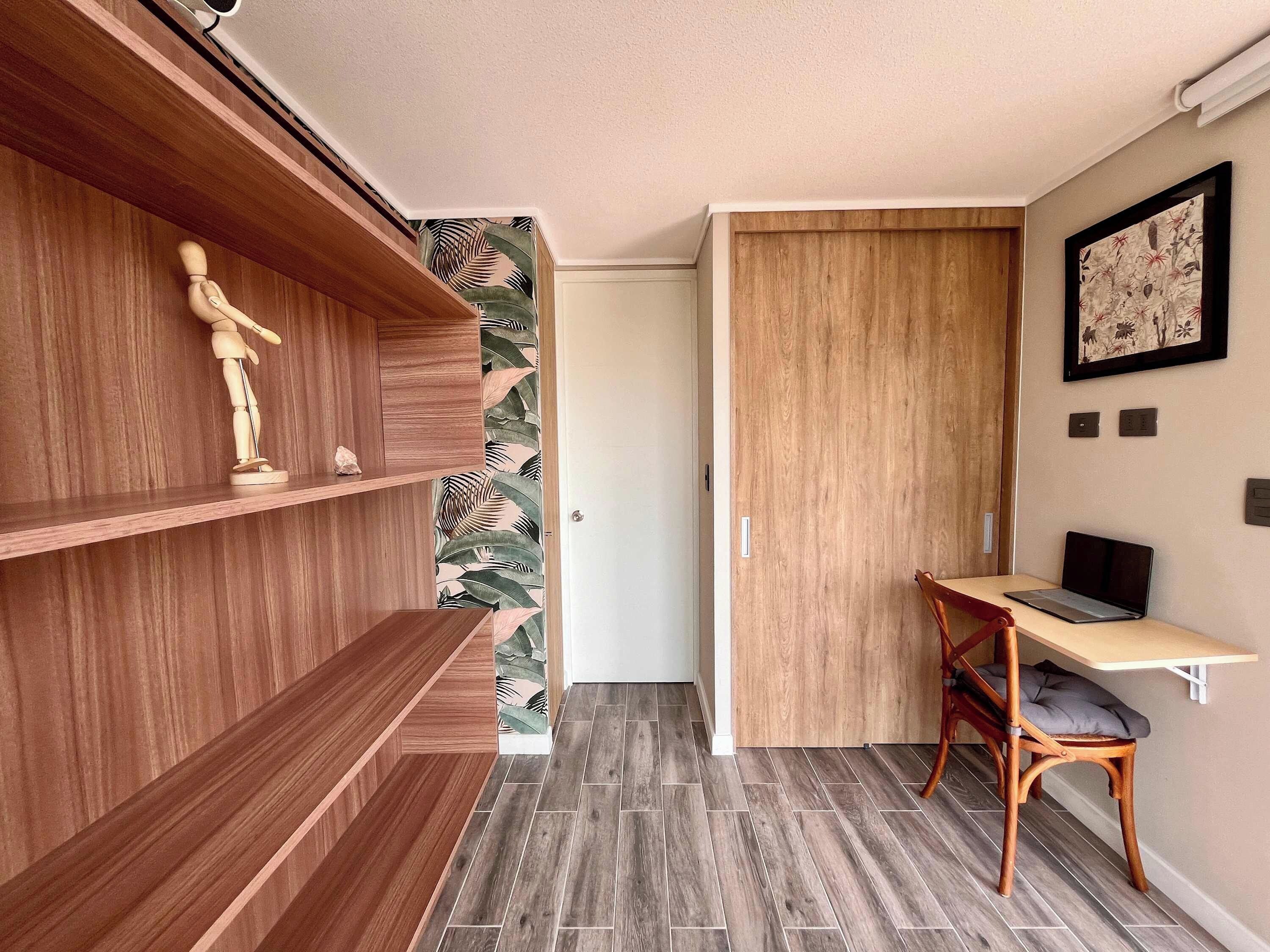 A compact room with a wooden desk, a chair, and built-in shelves.