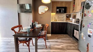 A modern kitchen with wooden cabinets, a built-in microwave, and a refrigerator with magnets. - Modern Ñuñoa Apt - Projector & Free Parking (Ñuñoa)