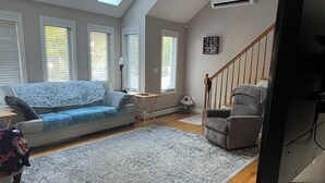 Ein Wohnzimmer mit Sofa, einem Sessel, einem Teppich und einer Treppe.