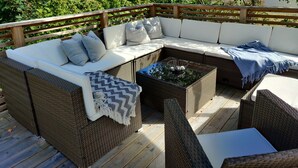 Eine Terrasse mit Korbmöbeln, darunter eine Couch und Stühle, sowie ein kleiner Tisch mit einer Schale.