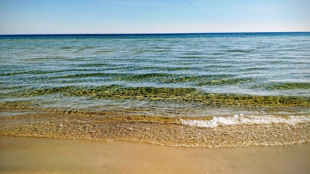 Ein Strand mit klarem Wasser und sandigem Ufer.