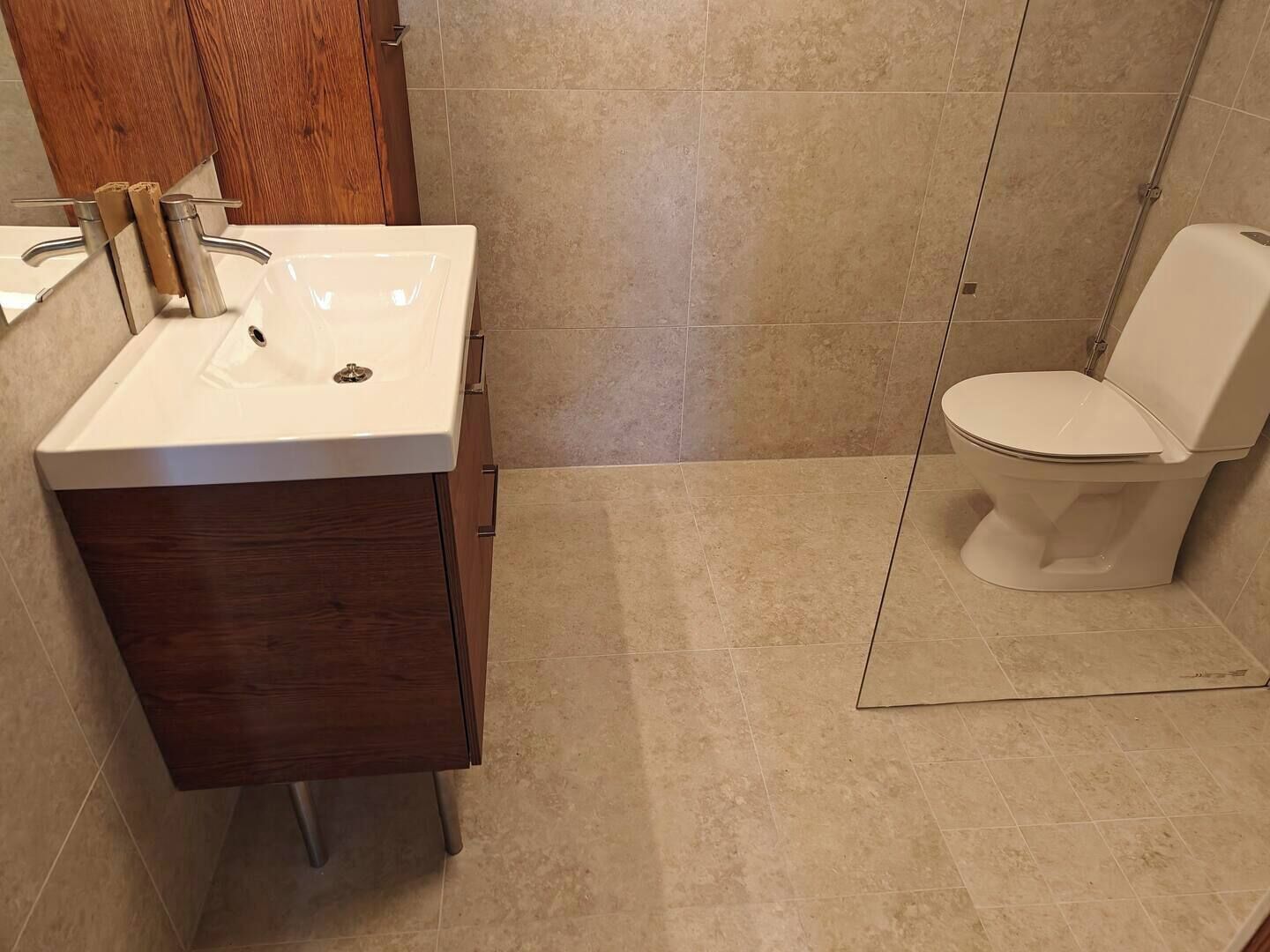 Une salle de bain avec un lavabo blanc, un meuble en bois et des toilettes.