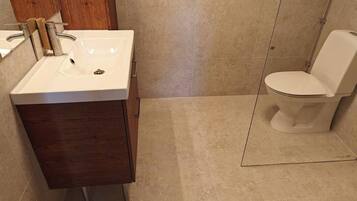 Une salle de bain avec un lavabo blanc, un meuble en bois et des toilettes.
