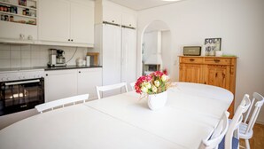 Eine moderne Küche mit weißen Schränken, einem weißen Esstisch und einem Blumenstrauß.