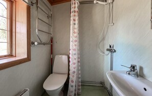 Un baño pequeño y funcional con inodoro, ducha y lavamanos.