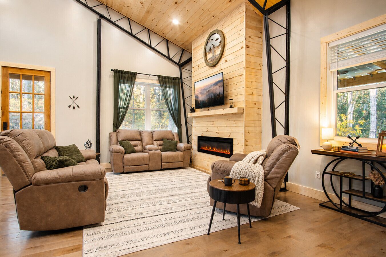 A cozy living room with a fireplace, a sofa, a recliner, and a TV mounted on the wall.