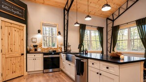 Une cuisine avec des meubles de rangement en bois, une cuisinière et une grande fenêtre avec des rideaux.