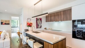 A modern kitchen with a central island, stainless steel appliances, and a minimalist design. - East Brisbane Stay - Balcony, Parking & City Access (East Brisbane)