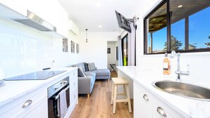 A modern kitchen with white cabinetry, a built-in oven, and a large window.