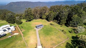 An aerial view of a property with a large grassy area, a small building, and a fenced enclosure.