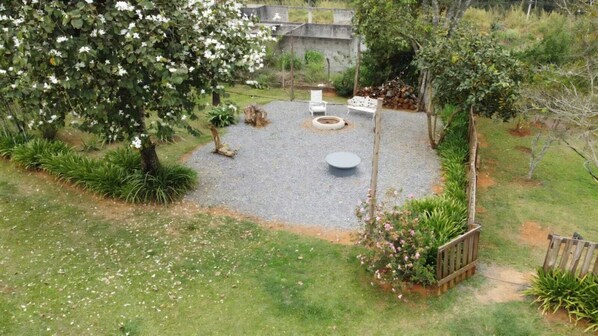 A circular outdoor seating area with a fire pit, surrounded by gravel and greenery.