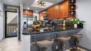 Una cocina moderna con armarios de madera, electrodomésticos de acero inoxidable y una isla central con taburetes de bar.