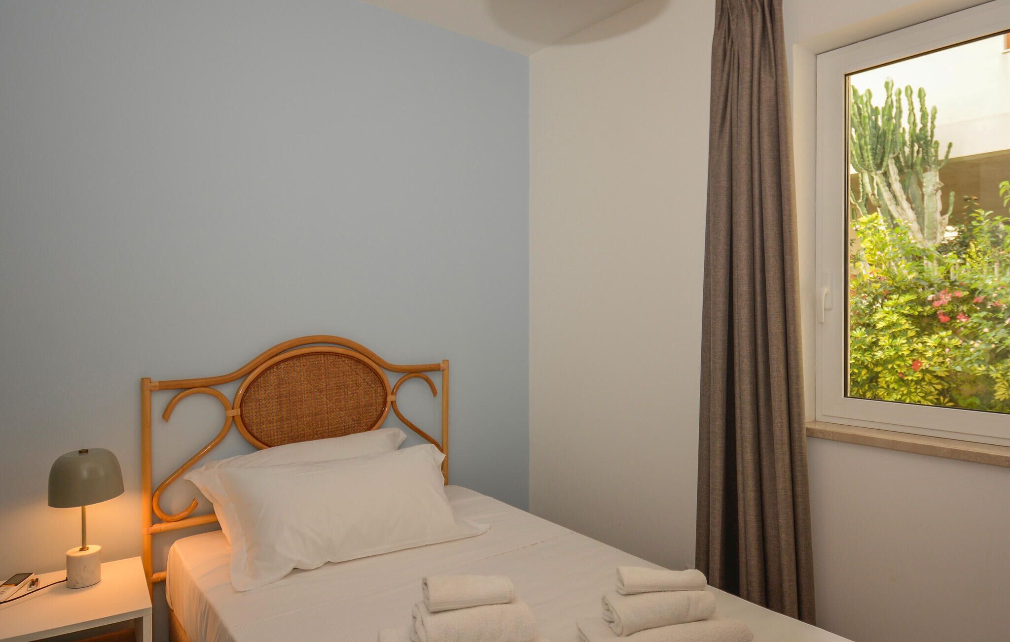 A single bed with a wooden headboard, white bedding, and a bedside lamp.