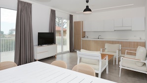 A modern apartment with a dining area, kitchen, and balcony.