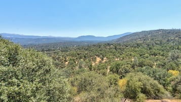 A panoramic view of a mountainous landscape with dense forest coverage and a clear sky.