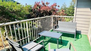 Een terras met een tafel en twee stoelen, omringd door een witte metalen balustrade.