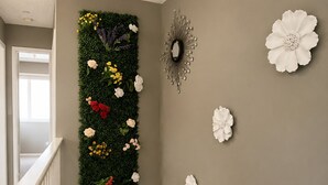 Een trap met een bloemstuk aan de muur, een spiegel en bloemen op de muur.