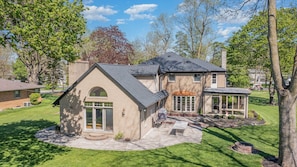 Ein zweistöckiges Haus mit großer Veranda, überdachter Terrasse und gepflegtem Rasen.