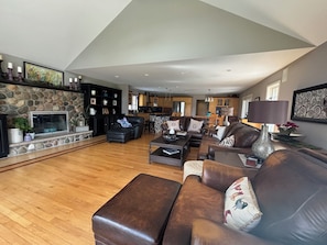 Ein geräumiges Wohnzimmer mit Kamin, Ledersofas und einem steinernen Kaminumrandung.