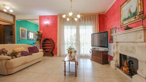Un salon avec un canapé beige, une table basse en bois, un téléviseur, une cheminée et un mur d’accent rouge.