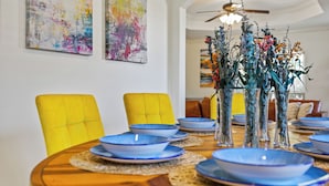 Een eettafel met blauwe borden, gele stoelen en decoratieve vazen met bloemen.