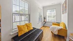 Een kamer met een zwarte bank, een gele fauteuil en een witte plaid.