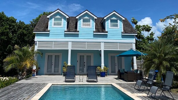 A two-story house with a swimming pool in front.