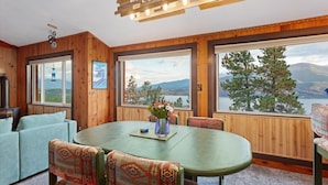 A wooden interior with a dining table, chairs, and a view of a lake and mountains. - Stunning Mountain & Lake Views 3BR Cabin with Hot tub (Twin Lakes)
