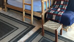 A cabin interior with a bunk bed, a sofa, and a woven bench. - The Superior Bunkhouse, a Cozy 16 X 24 Cabin near Grand Marais MN and Hovland MN (Hovland)