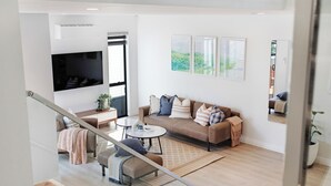 Ein modernes Wohnzimmer mit einer Couch, einem Couchtisch und einem an der Wand befestigten Fernseher.
